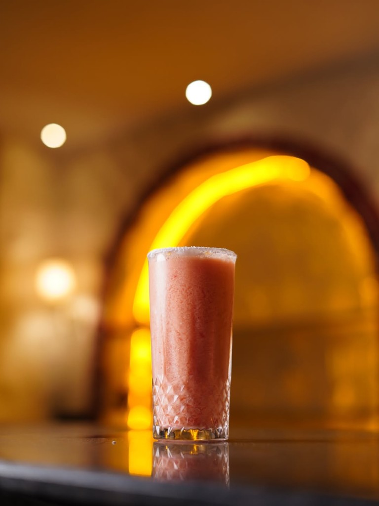 A tall pink drink against a warm arched light