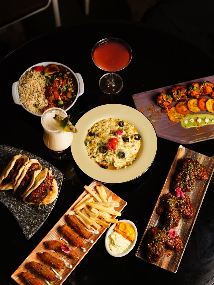 A shared table of pasta, starters, fries, and drinks