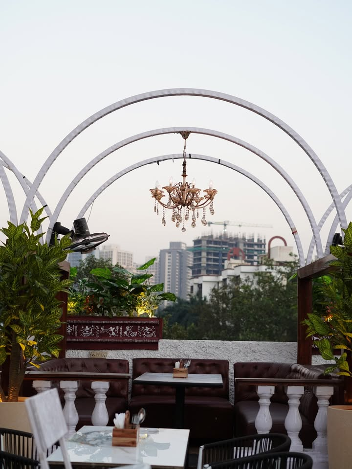 Crystal chandelier above a leather lounge with the city behind the arches