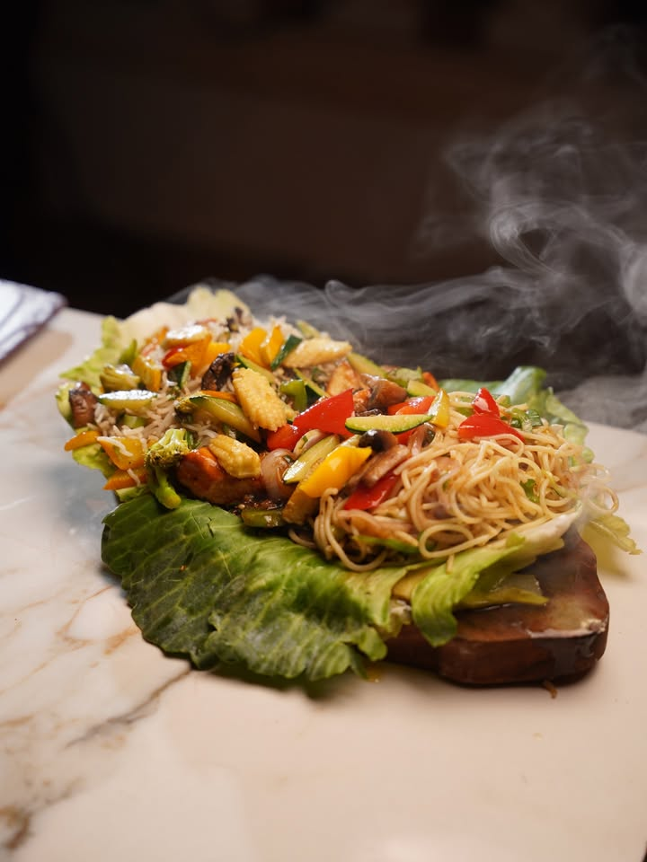 Steaming vegetable and noodle sizzler on lettuce